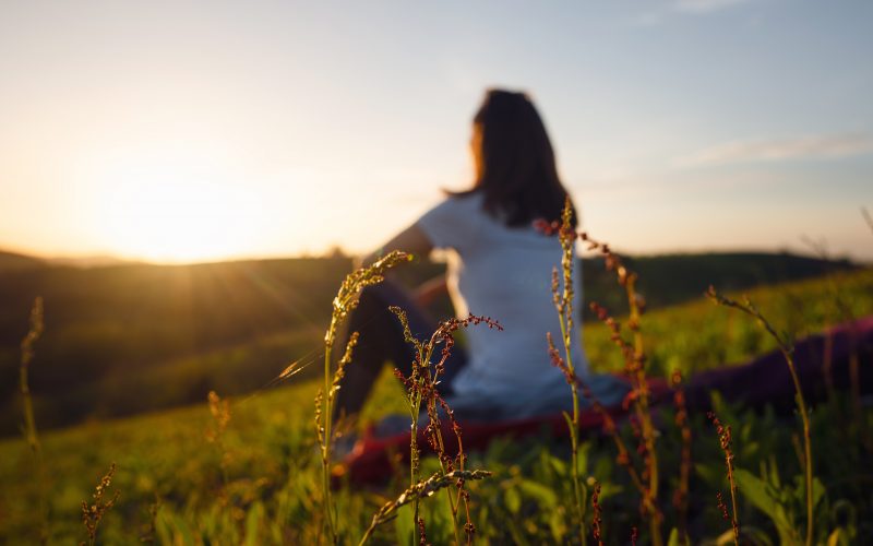 Blurred image of woman relaxing in nature, watching the sunset.