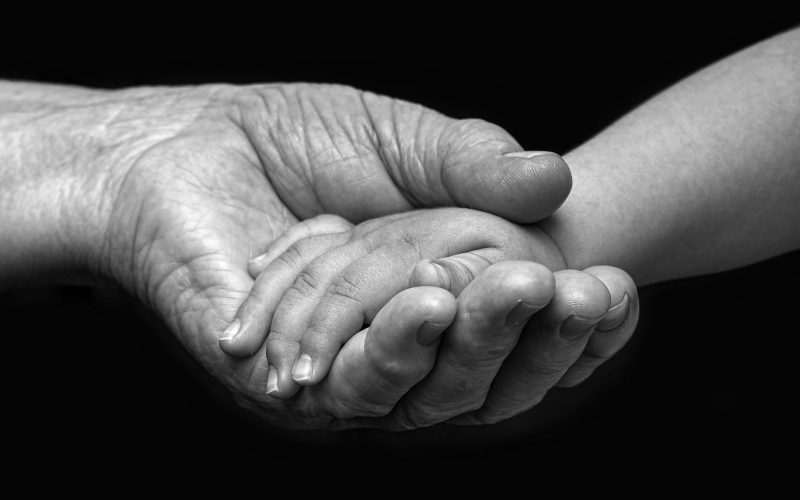 Image of an elderly woman and baby hands.