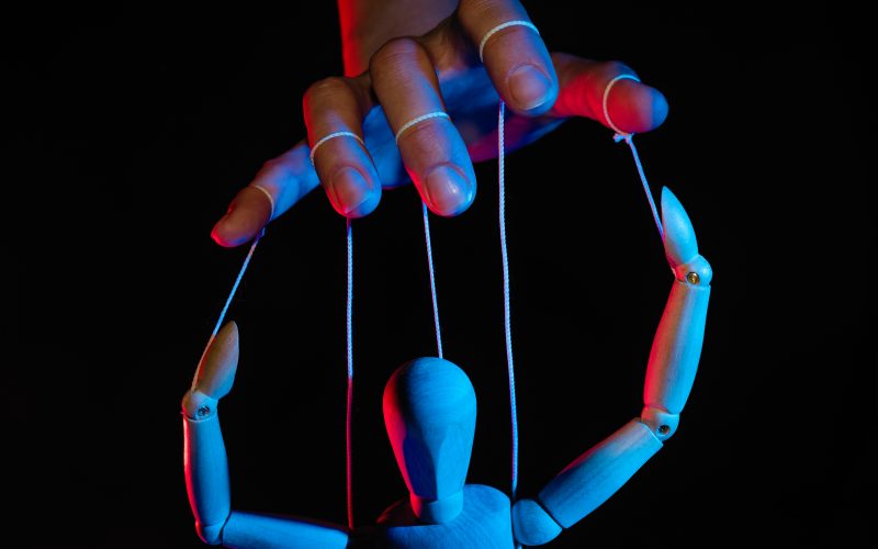 Photo illustration of a marionette in human hand.