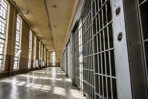 Photo illustration of prison bars and a hallway