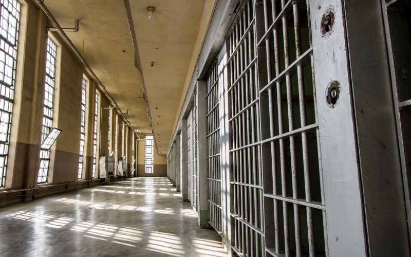 Photo illustration of prison bars and a hallway
