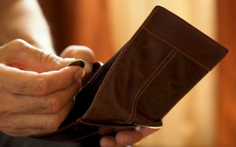 A person takes a coin out of their wallet.
