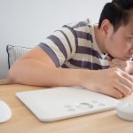 A man slouches in front of a computer