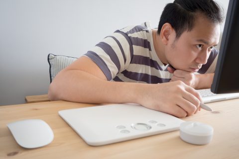A man slouches in front of a computer