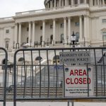 The front of the United States Congress building is blocked by a fence and a sign that says area closed.