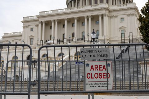 The front of the United States Congress building is blocked by a fence and a sign that says area closed.