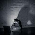 A woman sits in front of a computer with her head in her hands