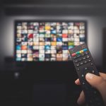 Someone points a remote control at a TV with lots of shows