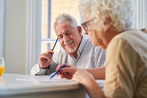 An elderly couple writing on paper at a table