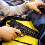 A student removes a gun from a backpack.