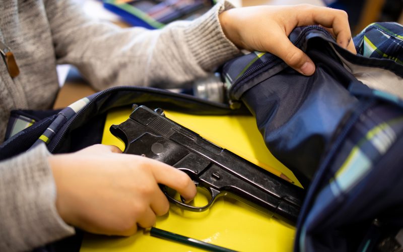 A student removes a gun from a backpack.