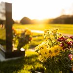 A grave stone with flowers at sunset