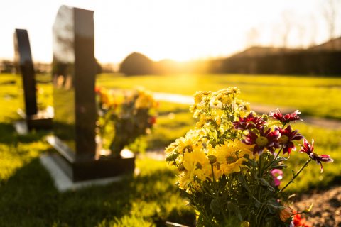A grave stone with flowers at sunset