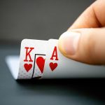 A poker player looks at their two hole cards -- the king and ace of hearts.