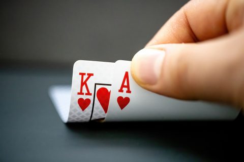 A poker player looks at their two hole cards -- the king and ace of hearts.