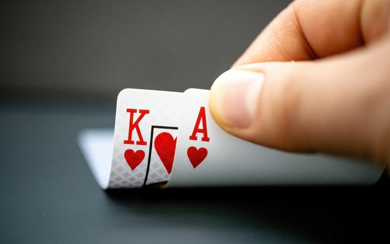 A poker player looks at their two hole cards -- the king and ace of hearts.