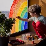 A child painting a rainbow on a window