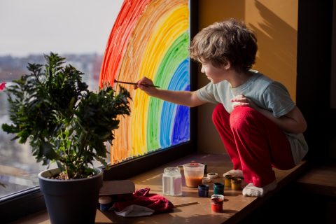 A child painting a rainbow on a window