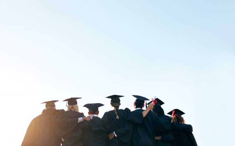 College graduates linking arms, shown from behind